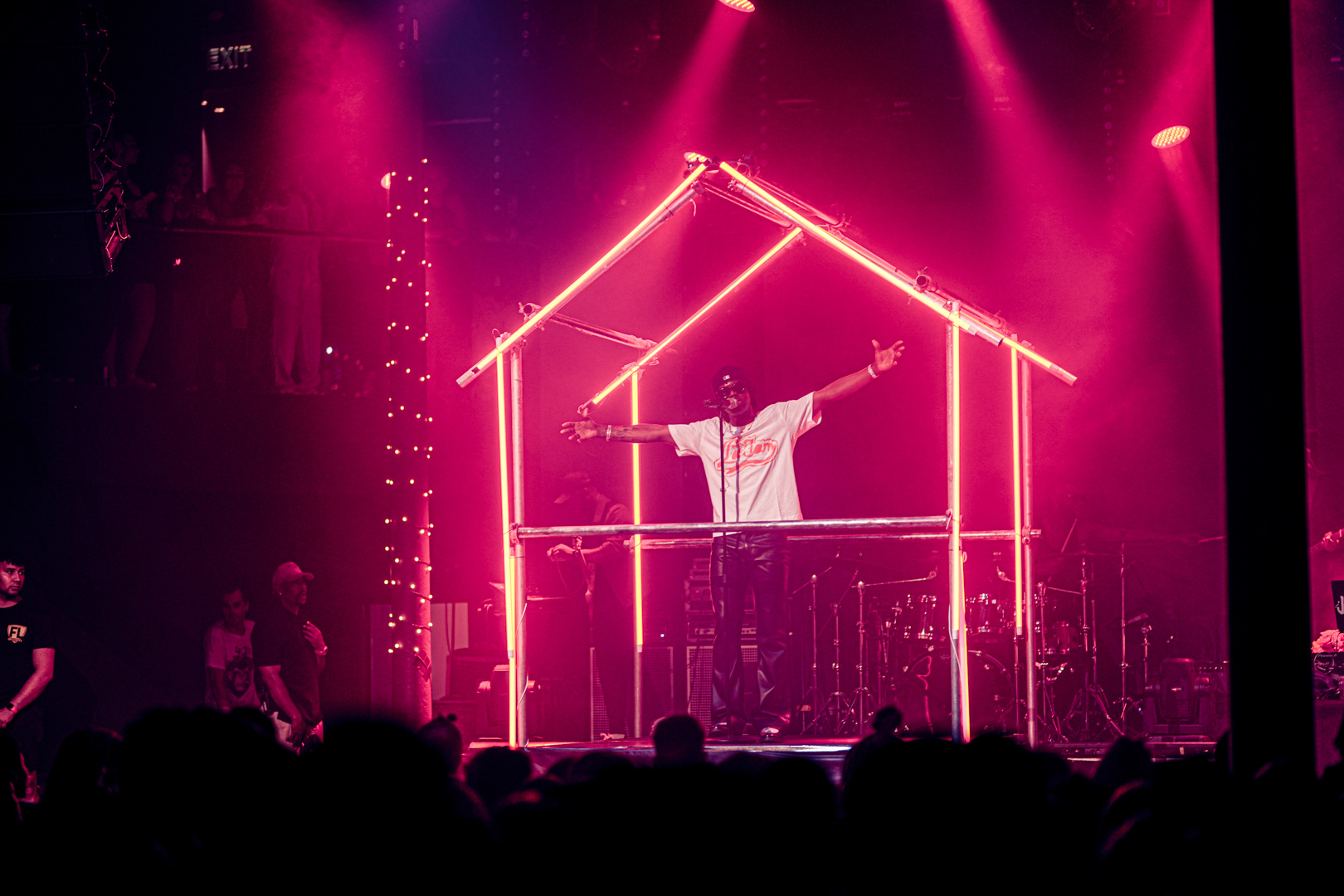 Rema on stage under a neon frame